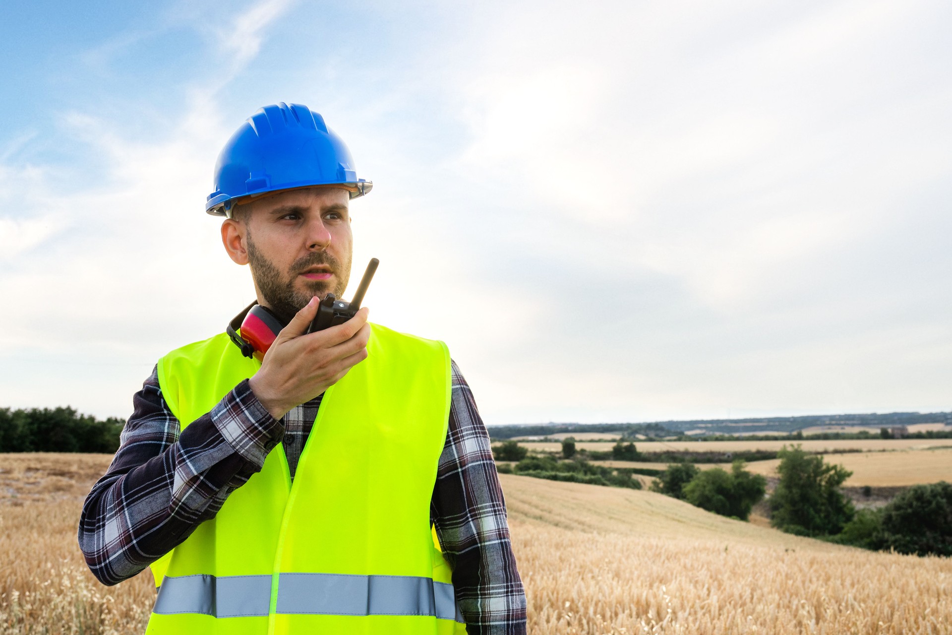 Male construction worker communicating with walkie-talkie. Copy space.