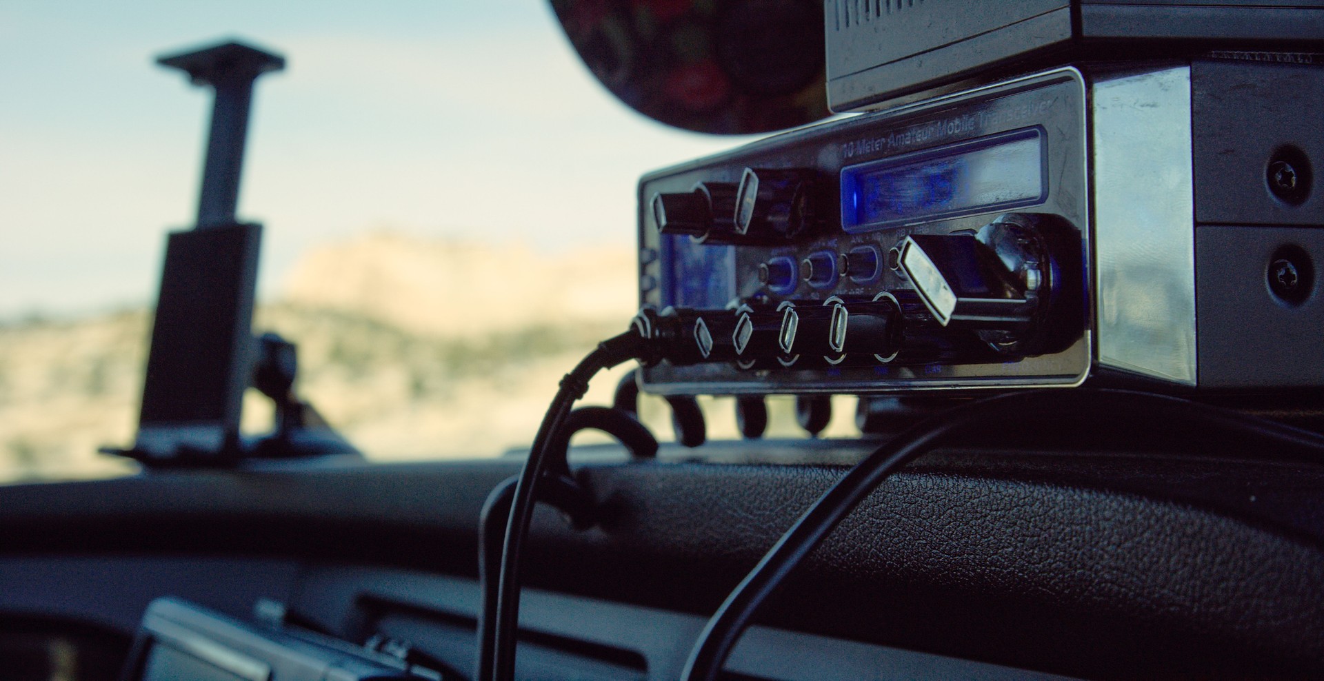 A CB Radio Sits on the Console of the Dashboard of a Semi-Truck on a Sunny Day